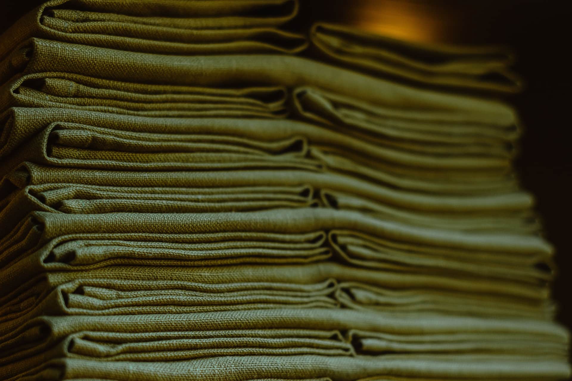 Folded teal and navy scrub tops stacked on a warm wooden surface