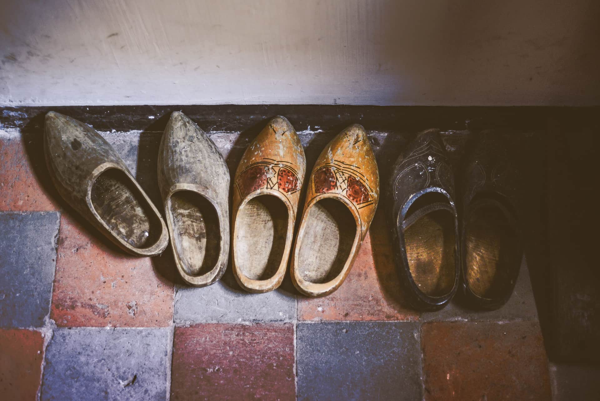 A pair of white leather nursing clogs resting on a pale hospital corridor floor